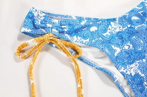 Close-up of blue paisley bikini with ruched side detail and yellow patterned tie