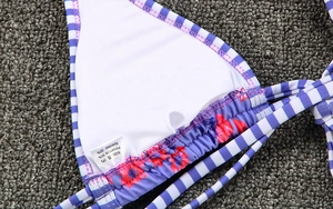 Detail of bikini top showing striped fabric, floral trim, and laundry care label