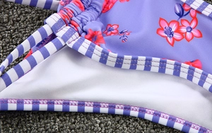 Detail of purple floral bikini fabric with striped straps and fine flat-lock stitching