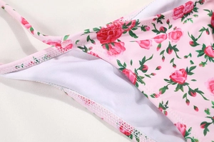 Close-up of pink bikini bottom fabric with red rose floral print and neat stitching