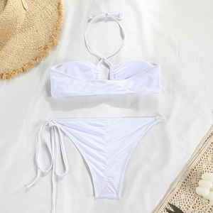 Flat lay of white two-piece bikini with ruched back detail and beach accessories