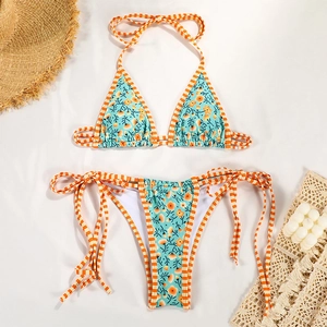 Flat lay of floral bikini set with blue pattern and orange straps on resort background