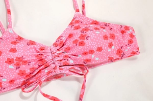 Close-up of pink floral bikini top featuring thin straps and front drawstring ruched detail
