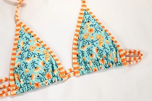 Detail of floral bikini top with light blue print and orange striped tie straps