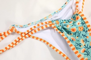 Detail view of floral bikini bottoms with contrast stripes and wash label showing S size