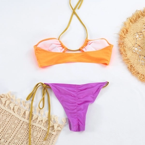 Détail à plat d'un bikini bicolore brillant avec liens latéraux et accessoires de plage