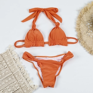 Detailed flat lay of orange knot bikini with side-ruched bottoms and sun hat accents