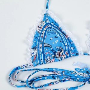 Close-up of blue floral bikini top with white lace trim and triangle halter straps