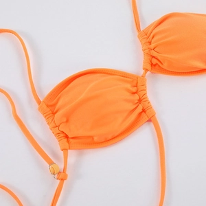 Makroaufnahme eines leuchtend orangen Bikini-Tops mit Raffung und goldener Metallschnalle