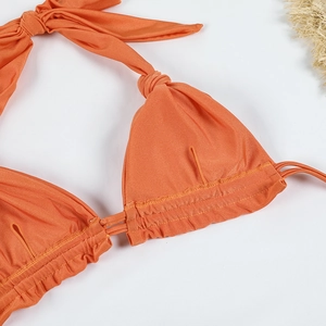 Detail of orange halter bikini top with shimmer fabric and a summer straw hat