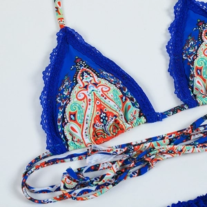 Détail d'un haut de bikini à motif paisley avec bordure en dentelle bleue vive