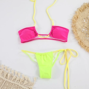 Vue à plat du haut de bikini rose et du bas vert fluo avec des accessoires de plage d'été
