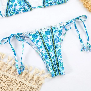 Detail of bohemian paisley print bikini with lace trim and tassel side ties on beach mat