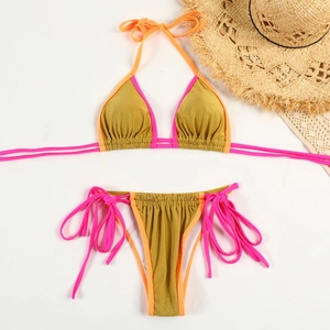 Flat lay of metallic gold bikini with pink trim, summer hat and lace details