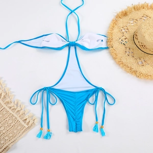 Detail of bright blue monokini with gold beads, tassels and lace beach accessories