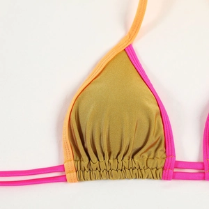 Detail of metallic gold bikini top with pink and orange contrasting straps and pleats