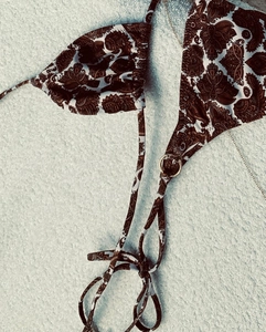 Detail of bohemian bikini top with brown paisley print and decorative gold metal rings