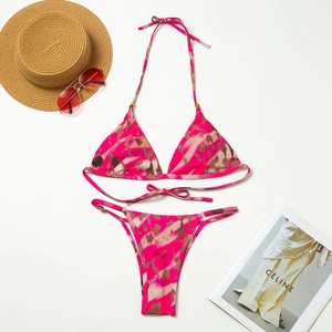 Detailed flat lay of pink camo bikini set with a straw hat and sunglasses