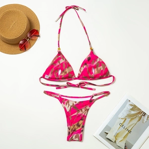 Flat lay of pink camo bikini set with metal rings, straw hat and stylish sunglasses