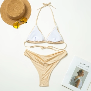 Flat lay of champagne bikini with removable pads, pleated briefs and summer accessories