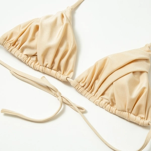 Close-up of champagne gold satin bikini top with pleated triangle cups and delicate ties