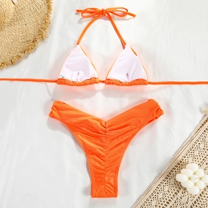 Detail of orange halter bikini top and pleated high cut bottoms on summer background