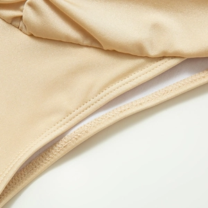 Detailed close-up of champagne gold bikini fabric with smooth texture and fine stitching
