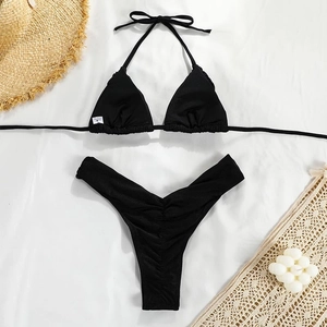 Flat lay of black pleated bikini set with textured fabric and summer holiday props