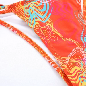 Detail of bright orange bikini fabric with colorful wavy patterns and precise stitching