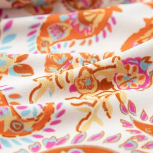 Macro view of colorful paisley print fabric featuring vibrant orange and pink patterns