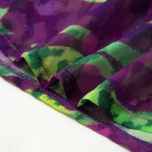 Detailed view of the purple and green printed mesh fabric with fine double-stitch edging