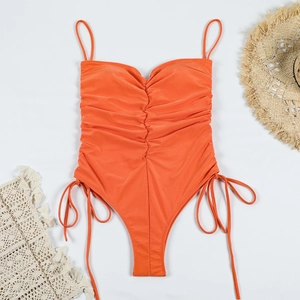 Détail d'un maillot de bain une pièce orange froncé avec lacets sur fond blanc