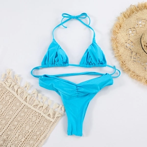 Detailed flat lay of bright blue ruched bikini with straw hat and beach accessories