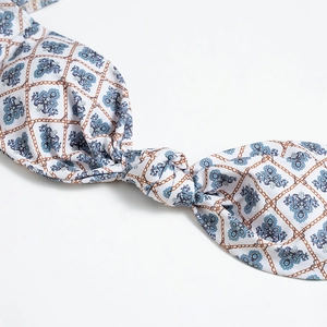 Dettaglio del pezzo sopra bikini bianco con motivi floreali blu e stampa a catena dorata