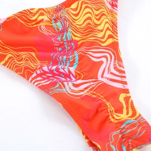 Macro detail of vibrant wave pattern print and durable stitching on orange bikini bottoms