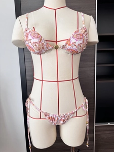 Detail of paisley print bikini top featuring a gold buckle and adjustable halter ties
