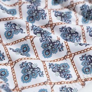 Dettaglio della stampa floreale vintage e catene su tessuto bianco per bikini