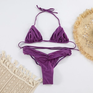 Flat lay of deep purple ruffled bikini set with beach accessories and straw sun hat