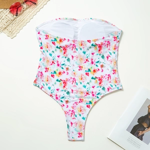 Detailed flat lay of floral bandeau swimsuit with removable padding and summer props
