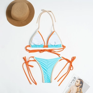 Flat lay of blue and orange bikini set with ties and resort props on white background