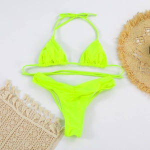 Detail of neon green pleated bikini set with textured fabric on white background