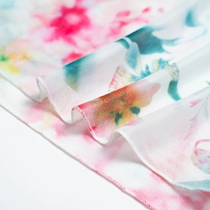 Close-up detail of sheer floral mesh fabric with vibrant pink and blue tie-dye print patterns
