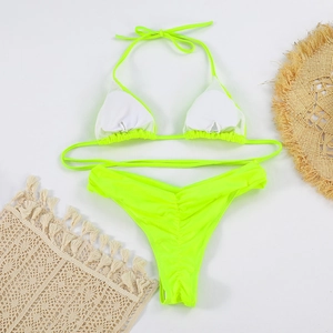 Detail of neon green bikini set featuring halter neck top and ruched bottom on beach decor