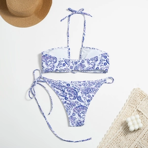 Flat lay detail of paisley print bikini set with straw hat and beach accessories