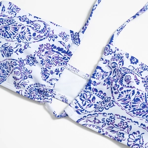 Close-up of white bikini top with purple paisley floral print and strap detail