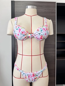 Detail view of floral print twist-front bikini set on a mannequin with ruched bottoms