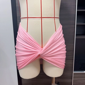 Dettaglio della gonna copricostume rosa con nodo centrale e texture di tessuto plissettato