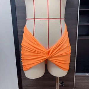 Dettaglio gonna da spiaggia arancione con design arricciato, nodo centrale e orlo a V