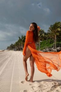 Détail d'une robe de plage en mousseline orange à fente haute flottant au vent