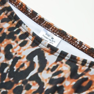 Macro detail of leopard print bikini fabric label showing size M and material composition
